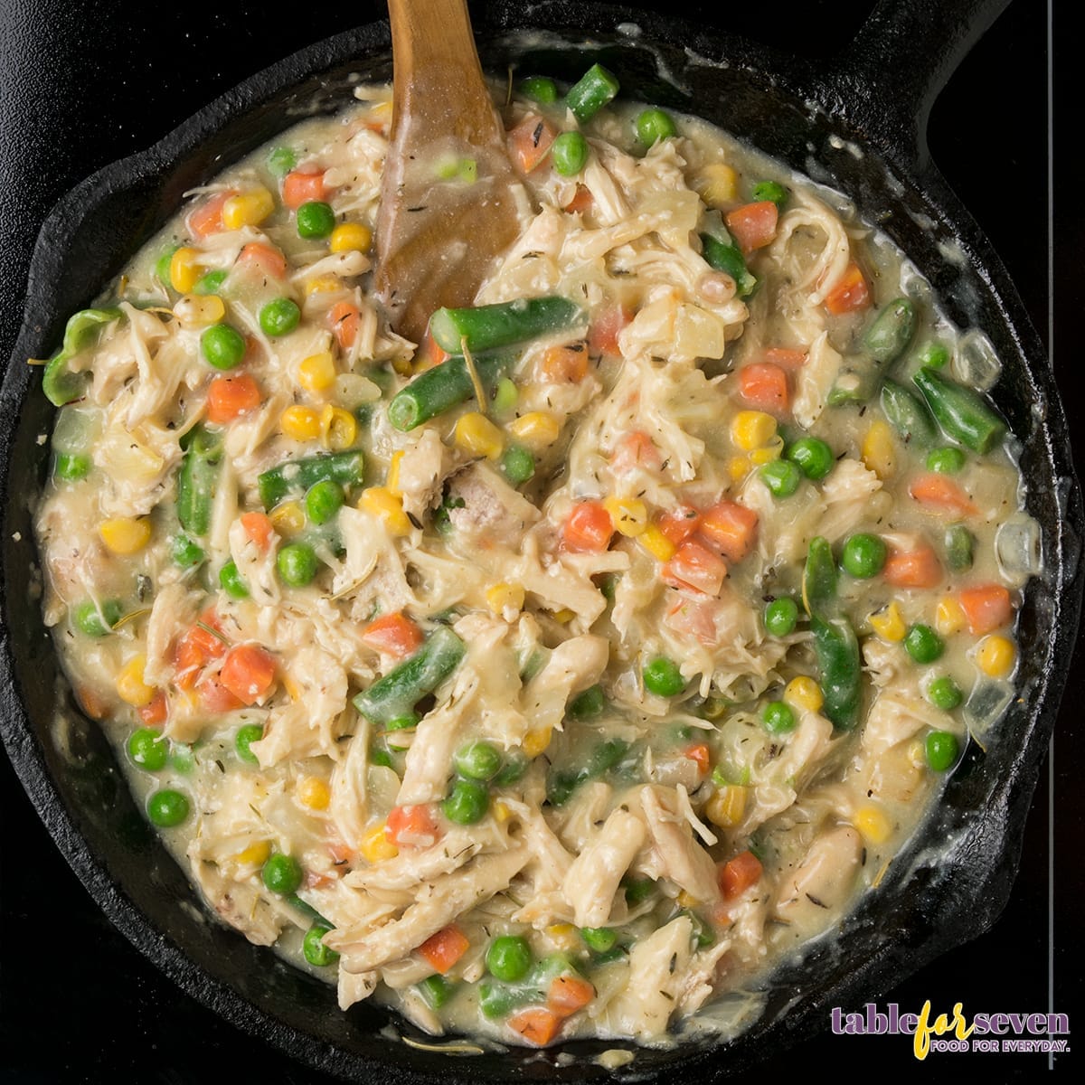 Mixing shredded chicken and vegetables in the creamy sauce