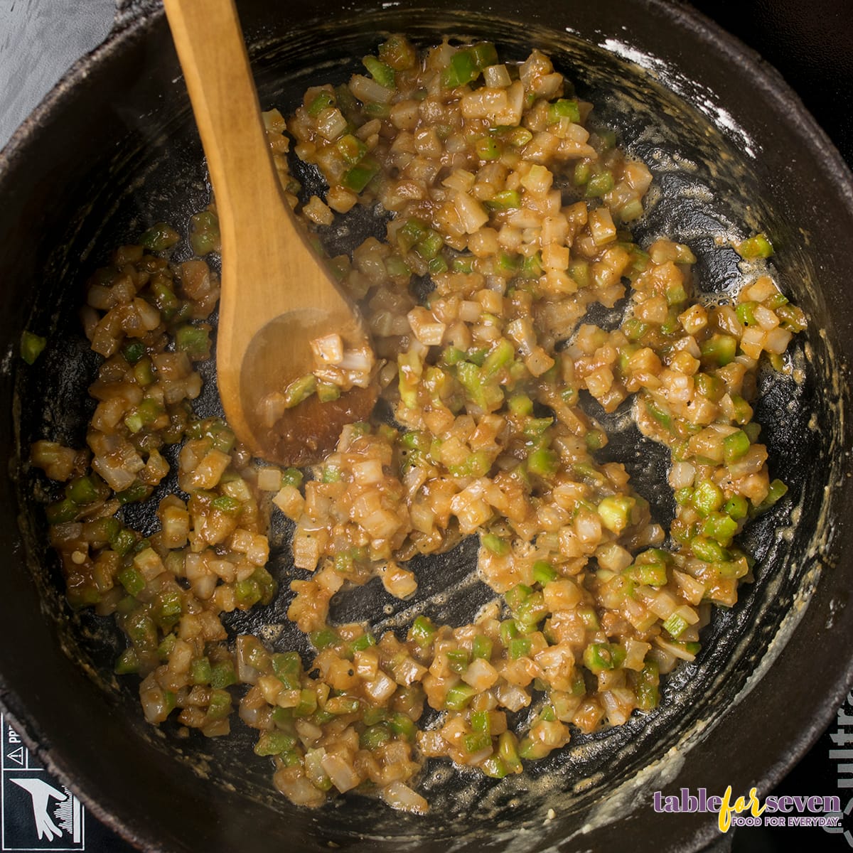 Chopped onions sautéing with green peppers in a black skillet