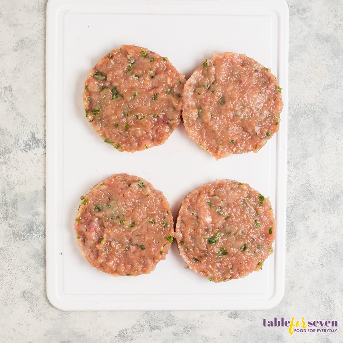 Uncooked turkey burger patties on a cutting board