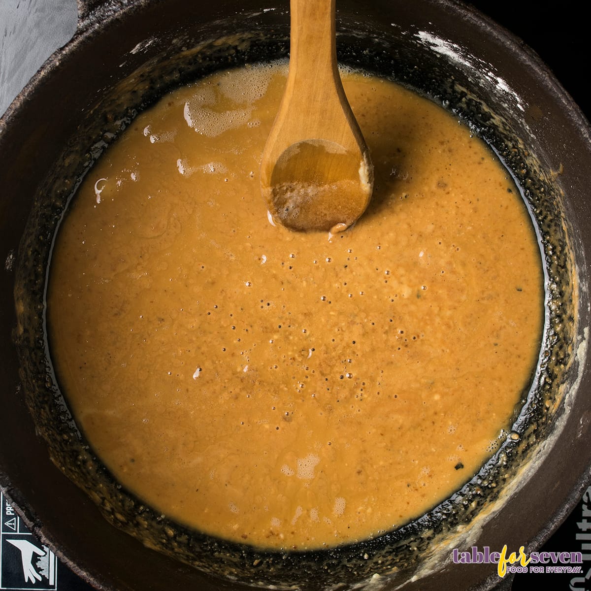 Thickened roux turning golden brown in a cast-iron skillet