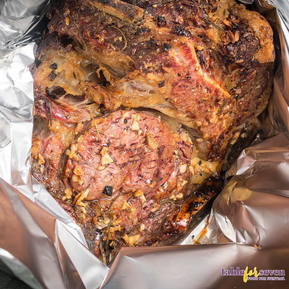 Prime rib covered in foil after roasting with garlic and herbs