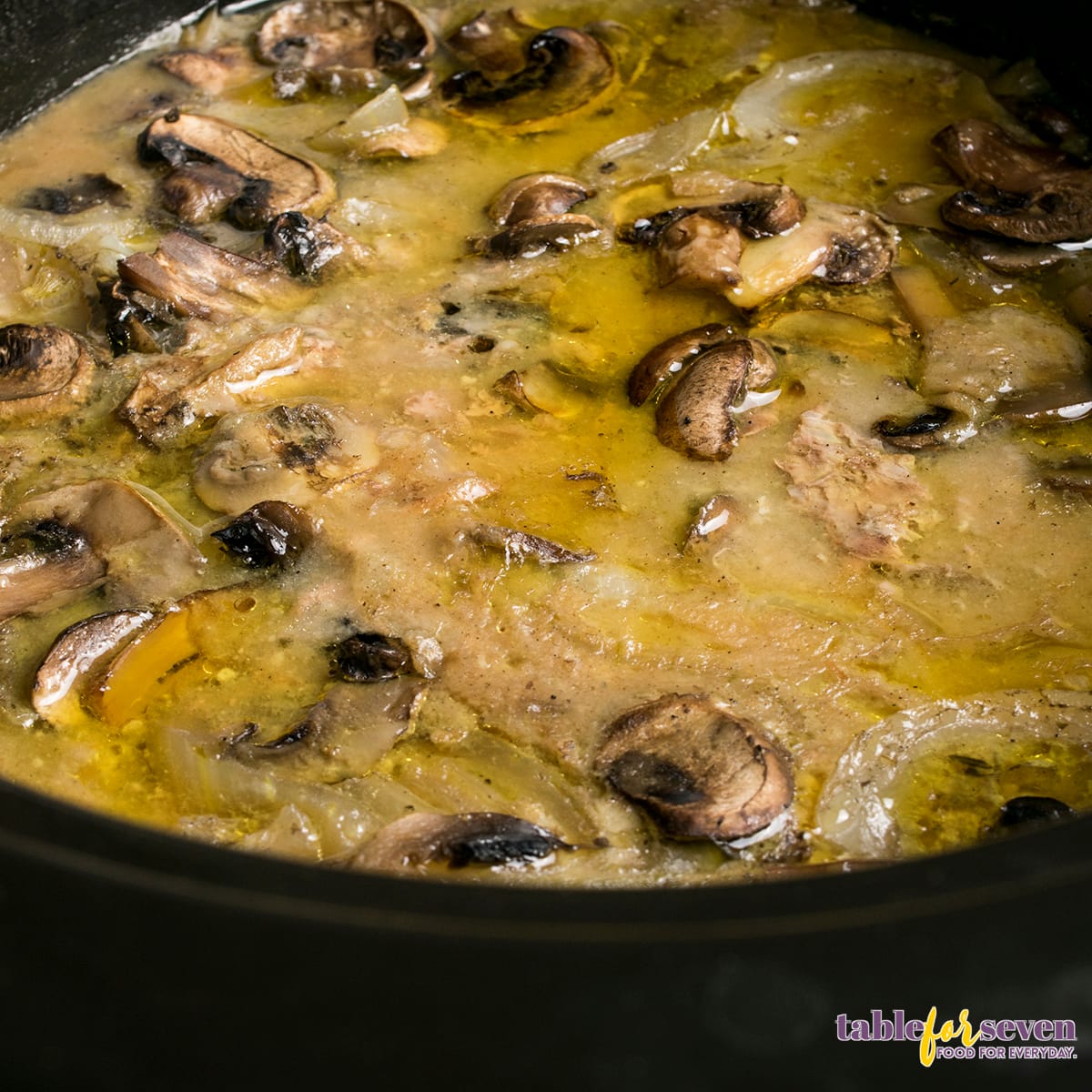 Cube Steak simmering in mushroom and onion gravy inside a crock pot