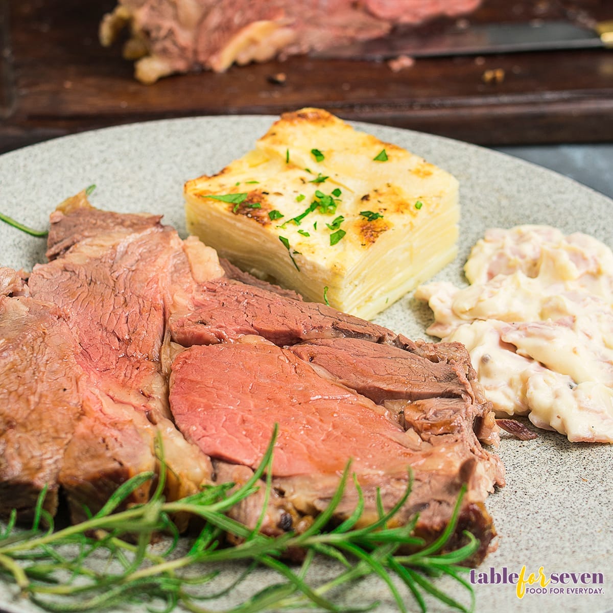 Sliced Gordon Ramsay prime rib served with potatoes and rosemary garnish