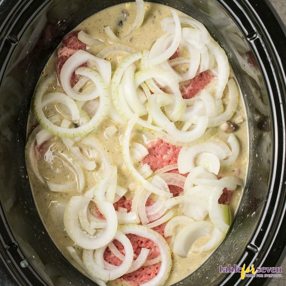 Sliced onions added to the Crock Pot for Cube Steak preparation