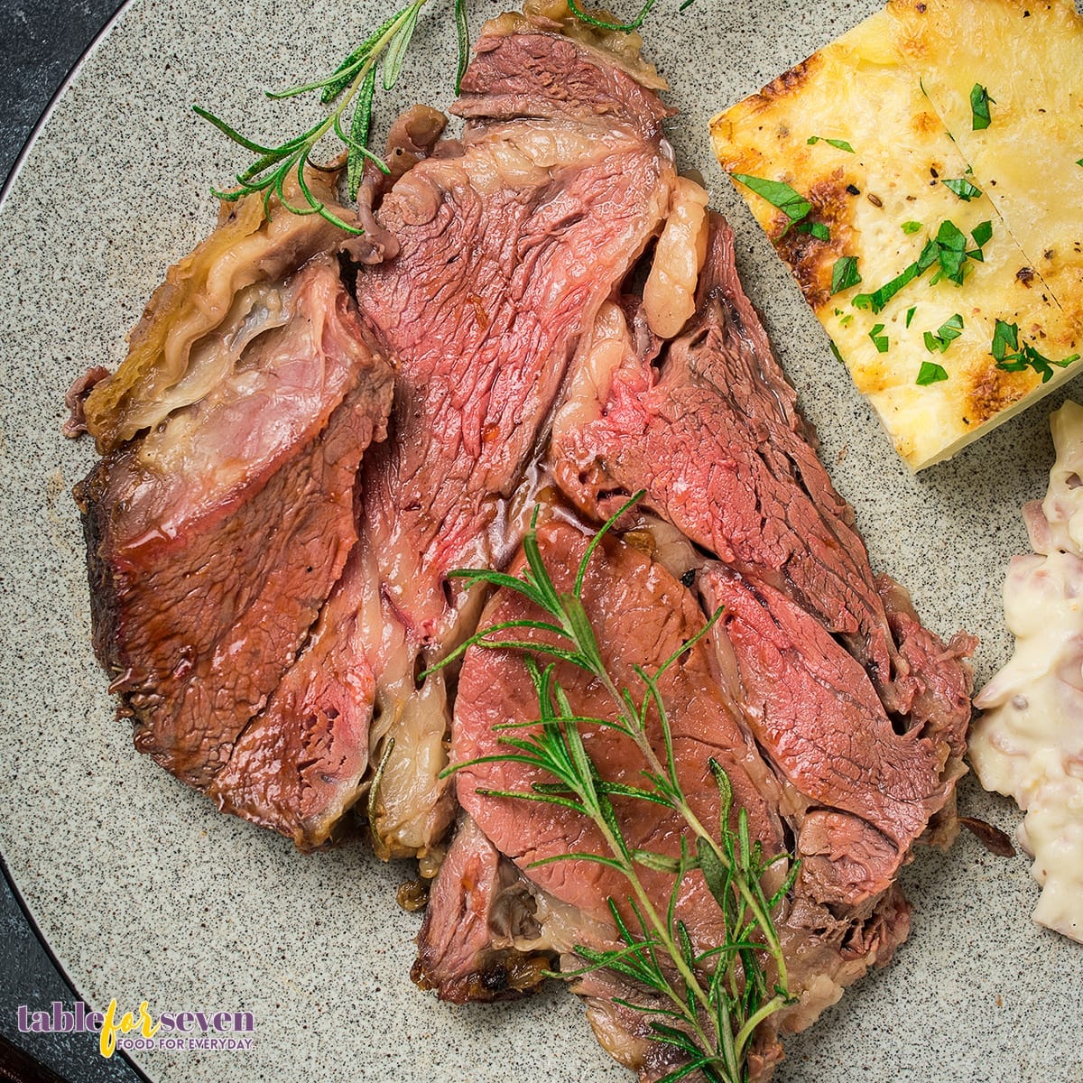 Prime rib served with scalloped potatoes and rosemary sprig