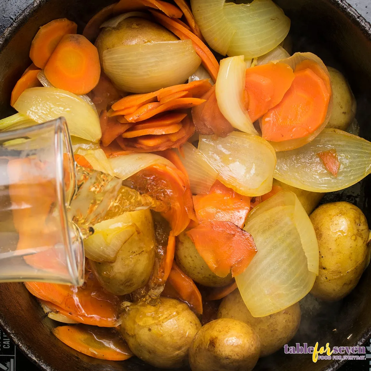 Pouring stock over vegetables in the Dutch oven