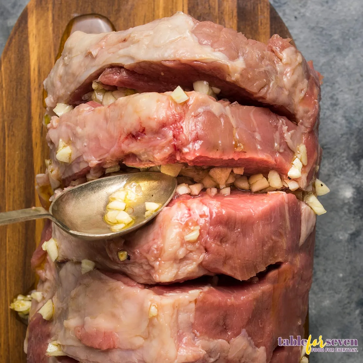 Stuffing garlic into the slits of the rump roast