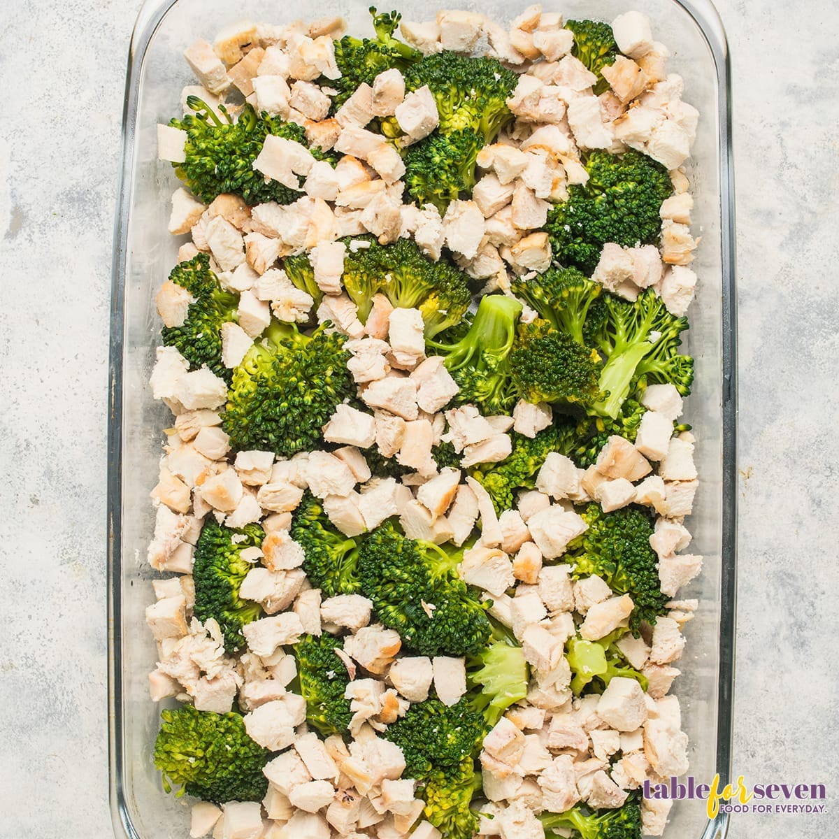 Layer of cooked chicken and broccoli in a baking dish