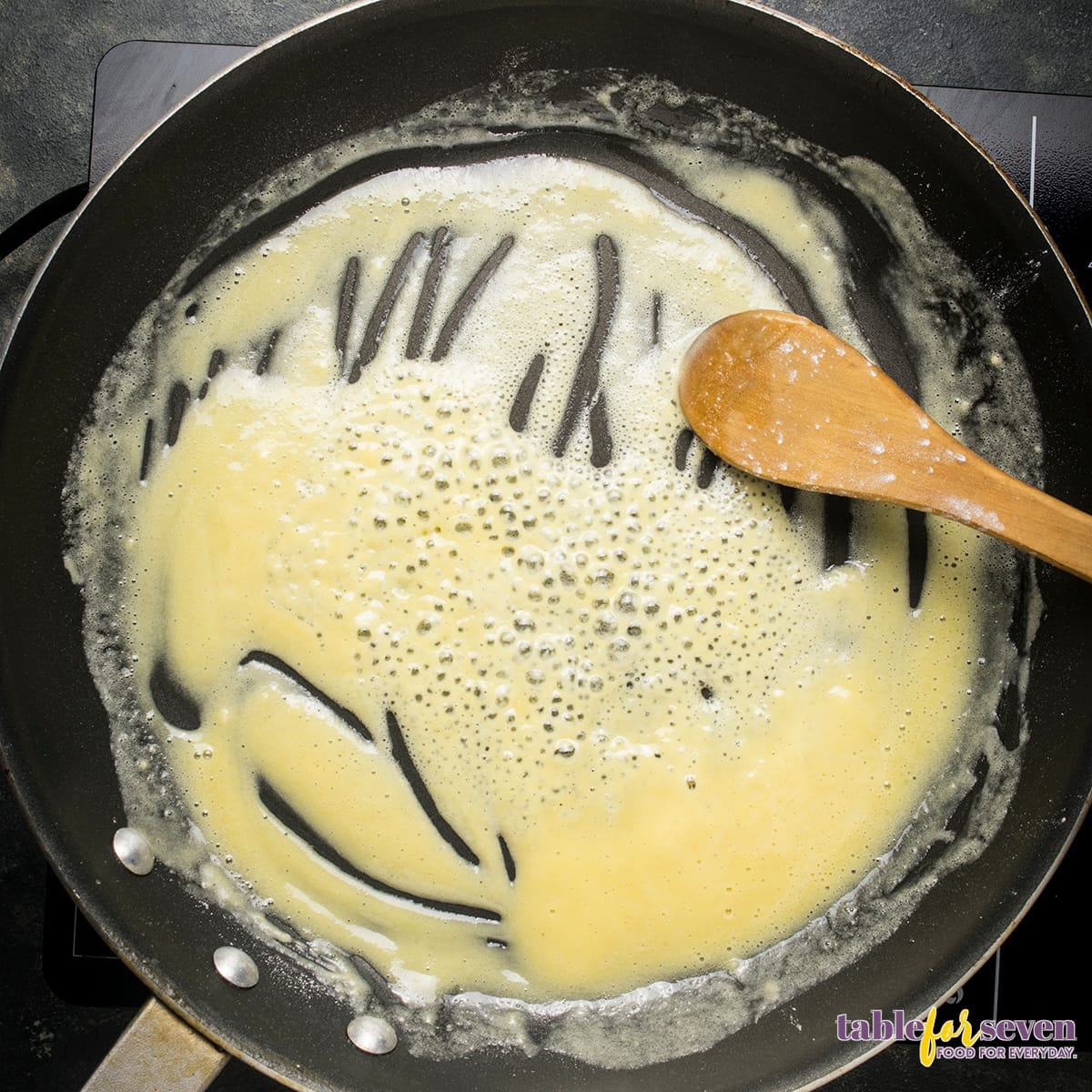 Flour being added to butter in skillet for roux