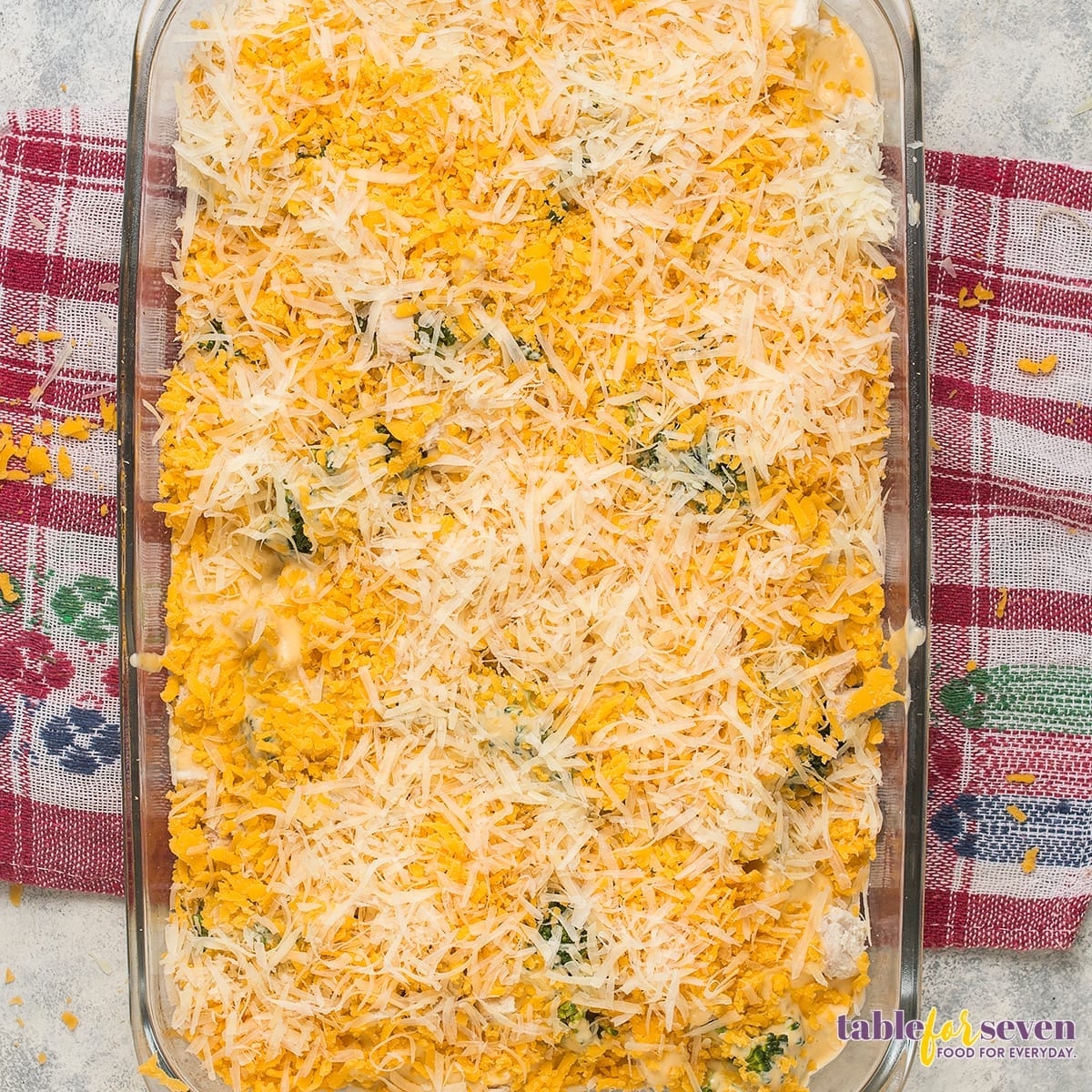 Shredded cheddar and Parmesan cheese topping over the chicken divan casserole