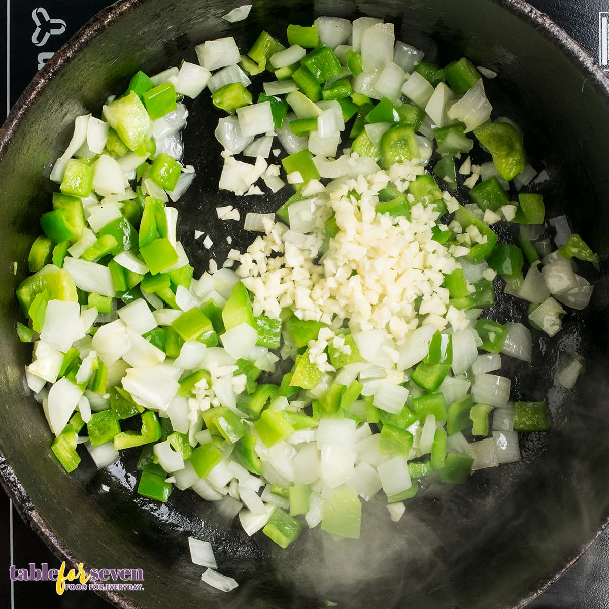 Minced garlic and fresh vegetables cooking in a skillet for Chicken Cacciatore