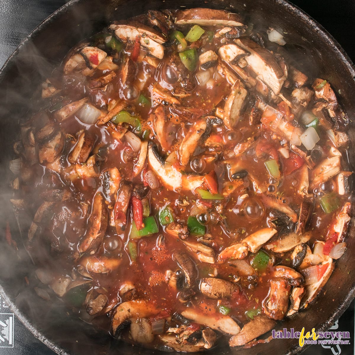 Rich tomato sauce with mushrooms and green peppers cooking in a skillet for Chicken Cacciatore