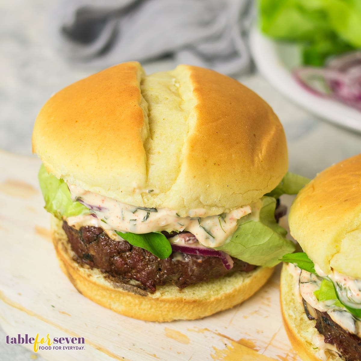 Top view of Gordon Ramsay Lamb Burger with sauce and vegetables