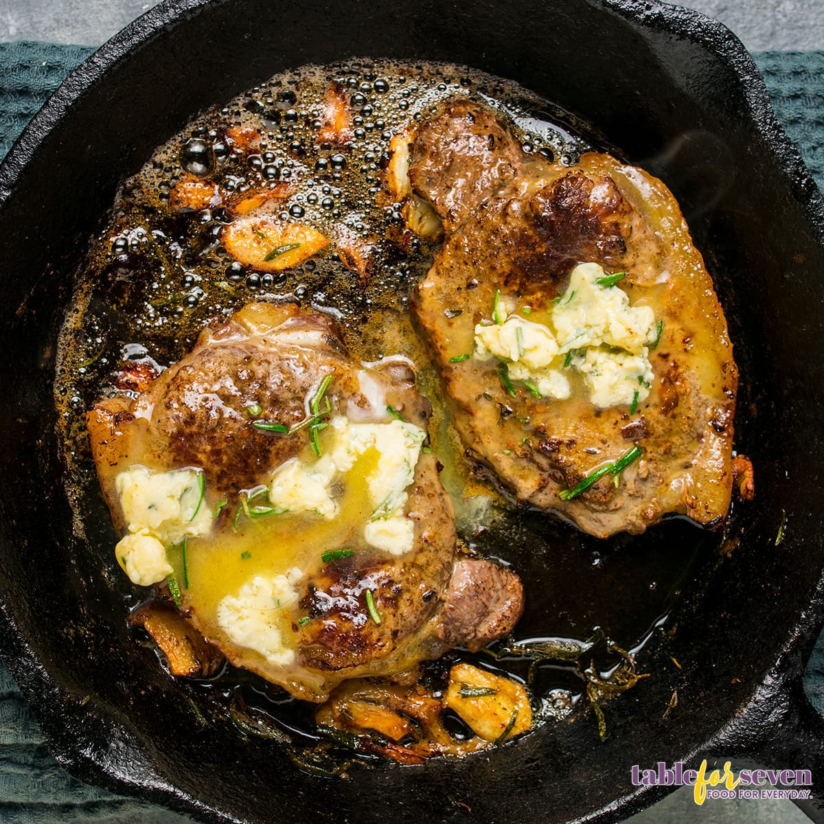 Steak cooking in a skillet with herb butter