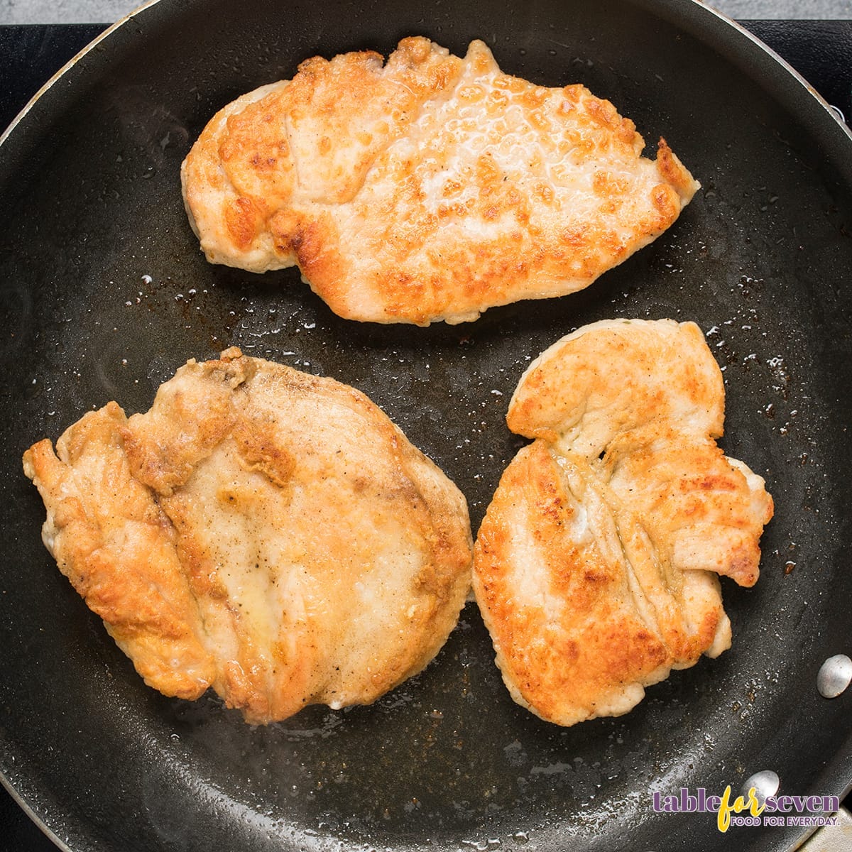 Chicken breasts frying in a skillet