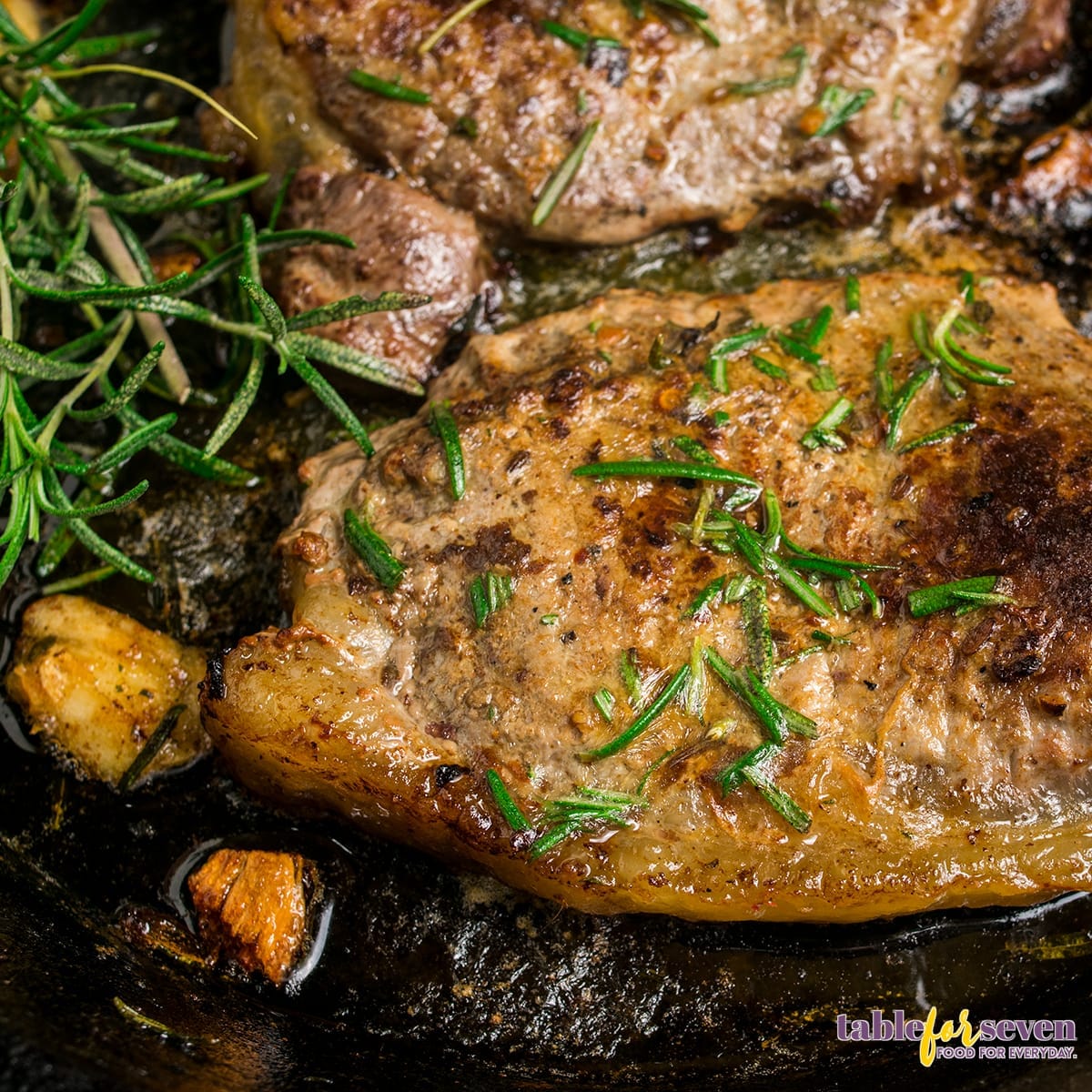 Close-up of steak with garlic and rosemary in a skillet