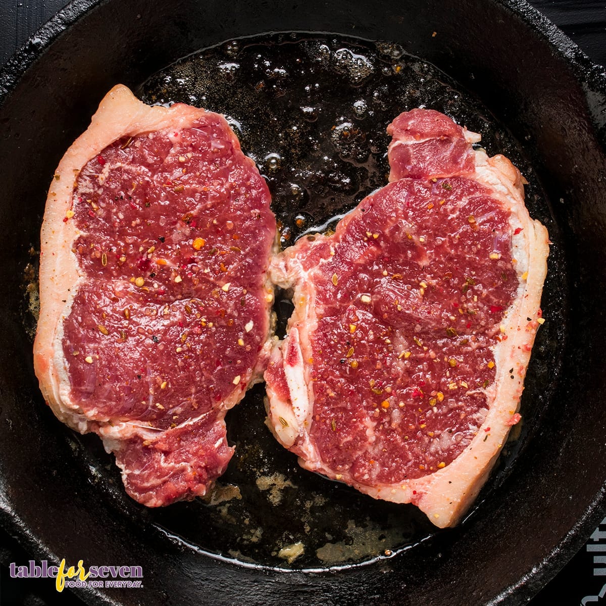 Raw steaks cooking in a skillet