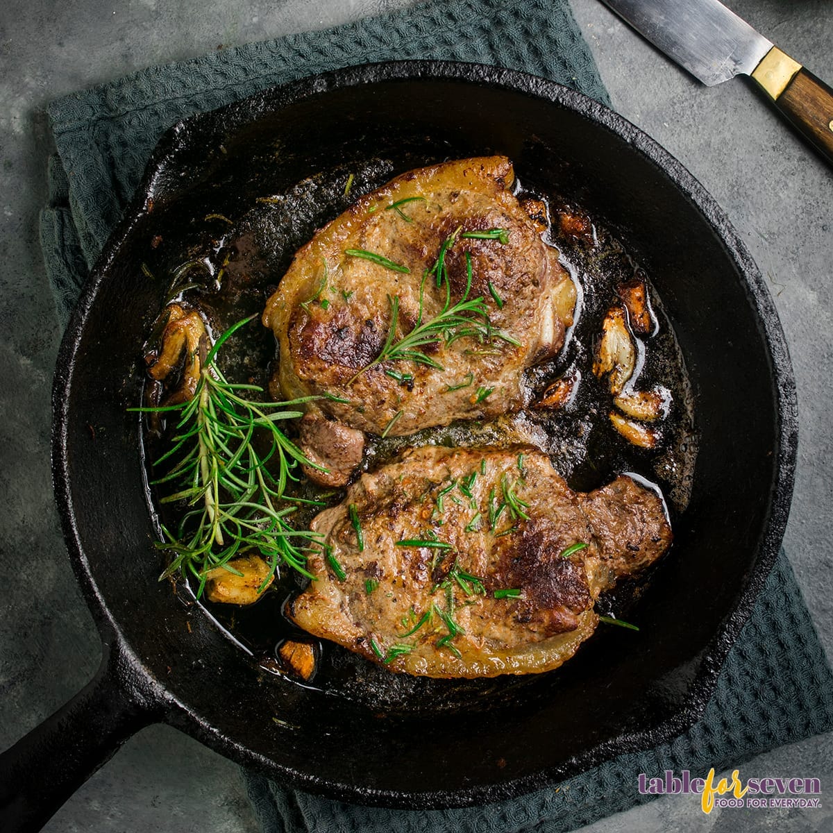 Steak cooking with garlic and rosemary in a cast iron skillet